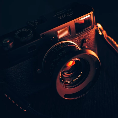 Appareil photo argentique noir éclairé par une lumière orangée