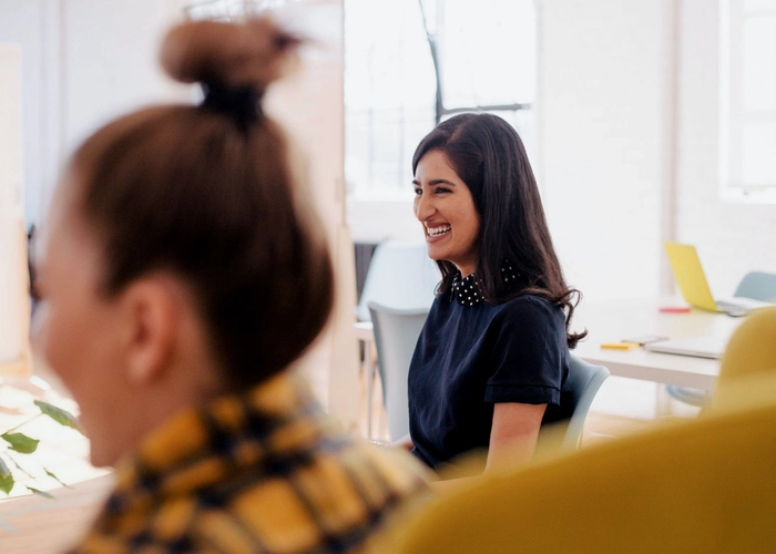 Femme assise dans un bureau, souriante, devant un ordinateur portable