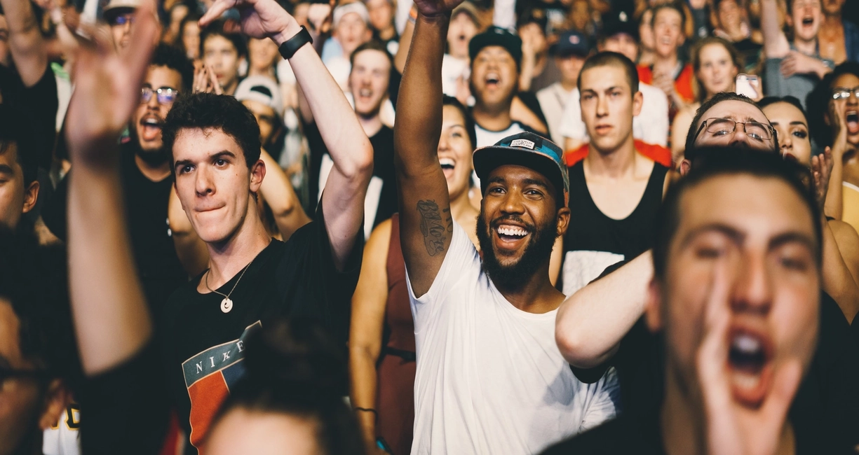 Foule enthousiaste lors d'un concert, des personnes lèvent les bras